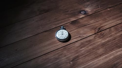 Silver Stopwatch Ticking on Wooden Plank Surface