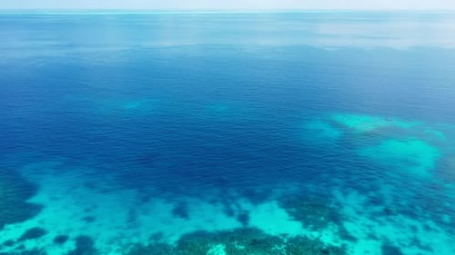 Wide angle above clean view of a paradise sunny white sand beach and blue sea background in vibrant