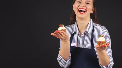 Woman Smiling Holding Two Cupcakes with Berries