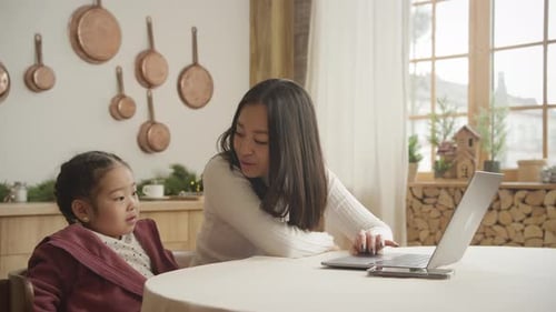 Woman and Child Using Laptop in Kitchen