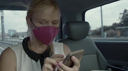 Female Taxi Passenger in Mask Surfing Net on Mobile