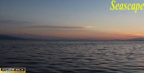 Sunset over calm ocean waters and distant mountains