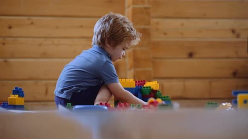 Child Playing with Colorful Plastic Bricks at Home . Toddler Having Fun and Building Out of Bright