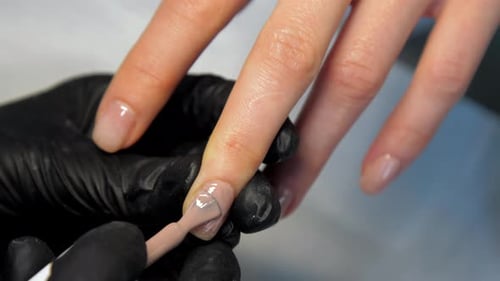 Manicurist Applies Beige Nail Polish to Woman's Nails