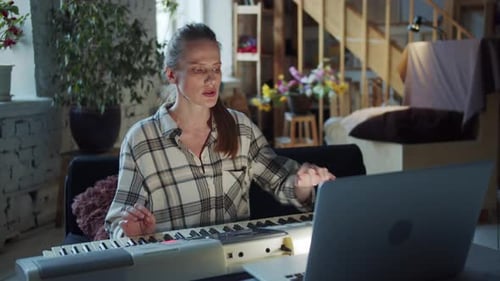 Woman Plays Keyboard and Uses Laptop at Home