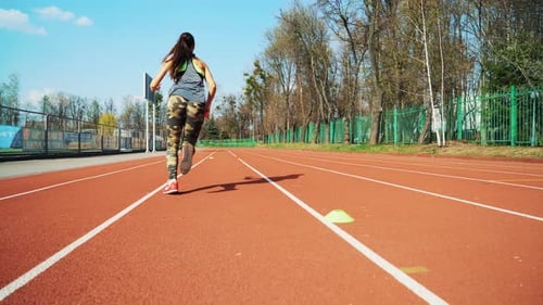 Young woman go in for sport run at the stadium track in the morning