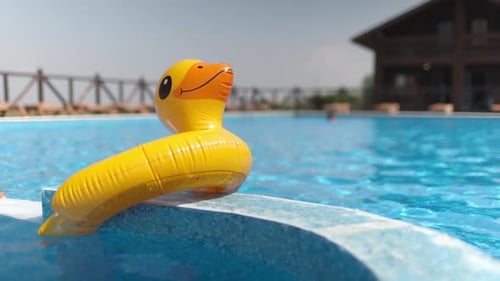 Eine aufblasbare Ente liegt an einem Sommertag auf einem lang ersehnten Meer an der Seite eines Pools mit klarem Wasser.