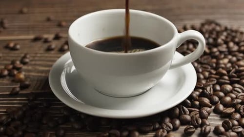 Pouring Fresh Coffee into Mug with Coffee Beans