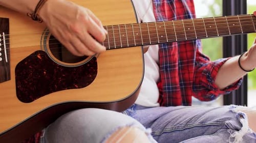 Jeune homme jouant de la guitare assis sur le rebord de la fenêtre