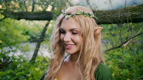 Portrait of Young Woman in Cosplay Elf Clothes and with Make-up on Green Background. Fantastic Look