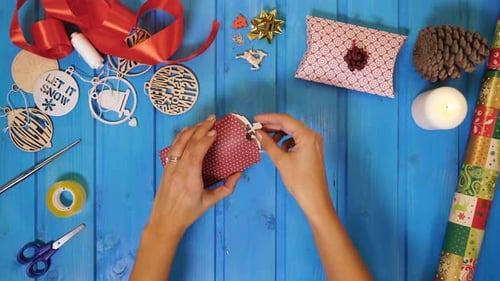 Hands Wrap Christmas Ornament in Gift Paper
