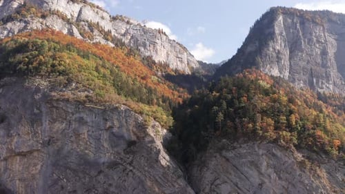 Beautiful Aerial of colorful forest on top of mountain, tilting down and revealing a small waterfall