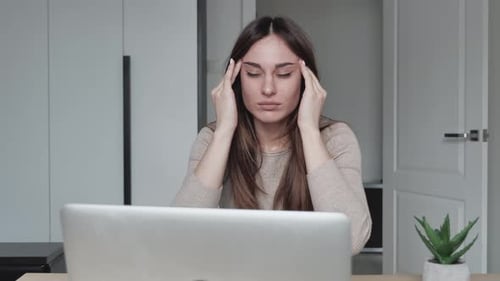 Jeune femme d'affaires assise au moniteur faisant un massage de la tête dans la maison de bureau moderne