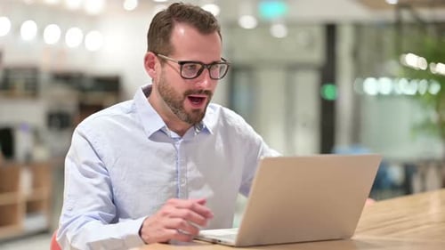 Excited Businessman Celebrating Success on Laptop in Office