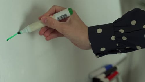 The Hand Draws a Line with a Green Marker on the Board