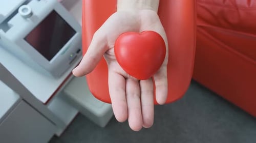 Hand Holding and Squeezing a Heart in Hospital