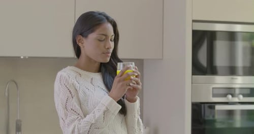 Woman Drinks Juice in Bright Modern Kitchen