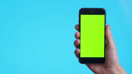 Hand Holding Smartphone with Green Screen on Blue