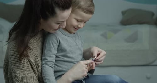 Caring Mother Trimming Child's Nails at Home