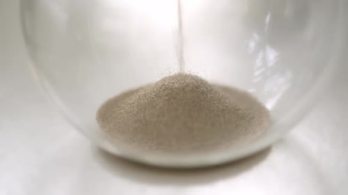 Sand Falling Through an Hourglass in Close Up