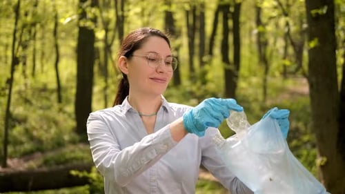 Una mujer con gafas pone basura en una bolsa