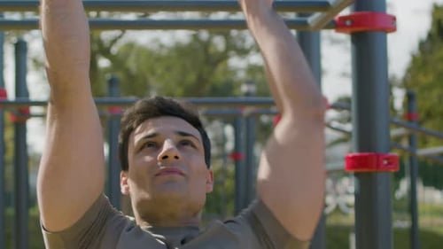 Muscular Caucasian Gay Doing Exercises on Bar Outdoor