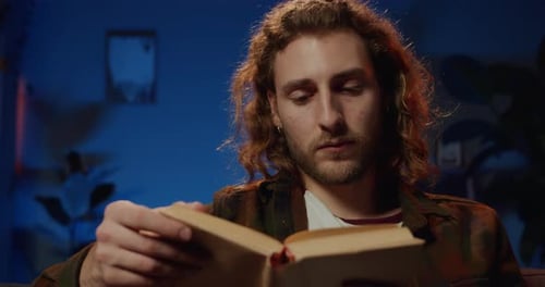 Close Up View of Concentrated Young Guy Turning Pages While Reading Literature. Smart Man with Long