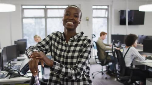 Portrait of smiling african american creative businesswoman sitting by desk in modern office
