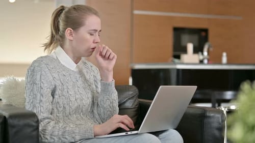 Woman Using Laptop While Coughing Indoors