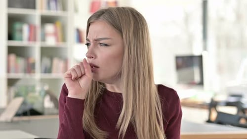 Young Woman Coughing with Sore Throat Indoors
