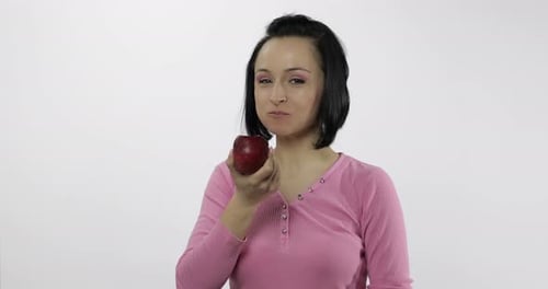 Young Beautiful Woman Eating Big, Fresh and Juicy Red Apple on White Background