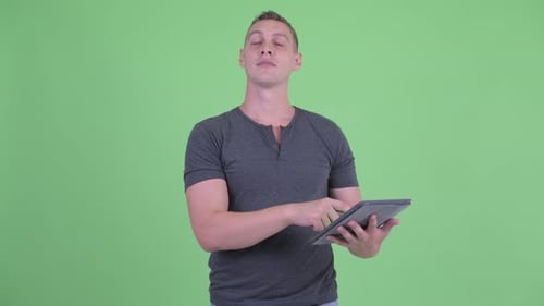 Young Adult Using Tablet Device on Green Background