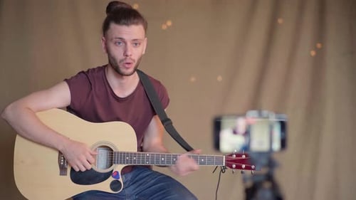 Young Adult Performing Acoustic Guitar for a Camera