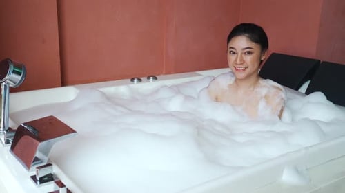 Woman Smiles in Luxury Bubble Bath in Bathroom