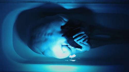 Man in Bathtub Under Dramatic Blue Light