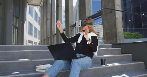 Woman in Casual Clothes which Sitting on Building's Stairs in Virtual Reality Headset and Working
