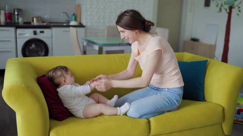 Mother Interacts with Infant on Yellow Sofa