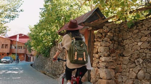 Woman Riding Bike on Cobblestone Street