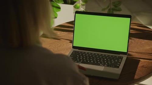 Handheld Shot of an Unrecognisable Caucasian Woman Watching a Laptop Computer with Green Screen