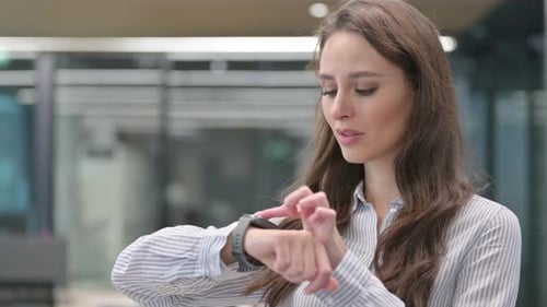 Young Woman Interacting with Smart Watch in Office