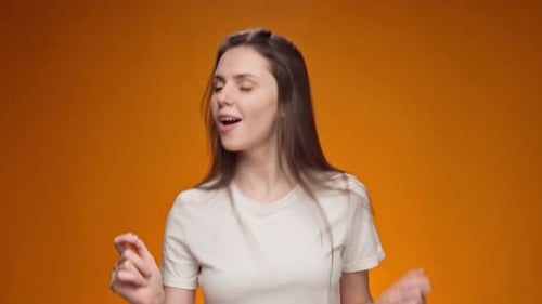 Energetic Woman Dancing Against Orange Background