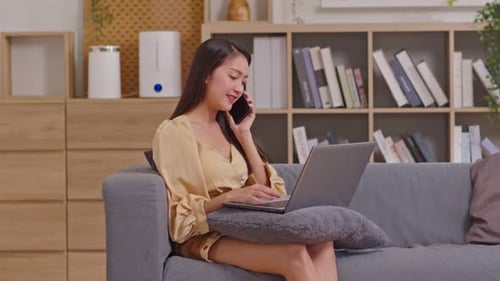 Woman Working on Laptop and Talking on Phone