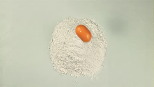 The Super Slow Motion of the Egg Falls Into a Pile of Flour on the Table with Splashes