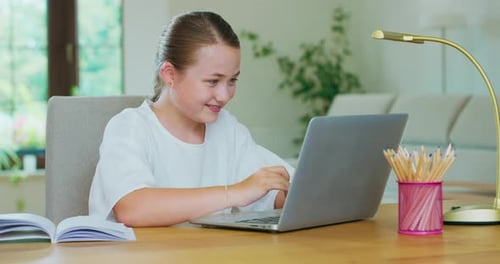 Girl Using Laptop Computer at Desk in Home