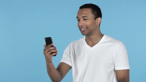 Young Adult Man Using Smartphone on Blue Background