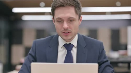 Man in Suit Talking On Laptop