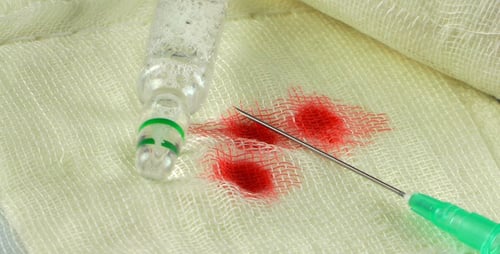 Medical Needle and Ampule with Blood on Gauze