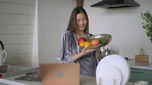 Smiling Woman with Fruit Bowl in Kitchen