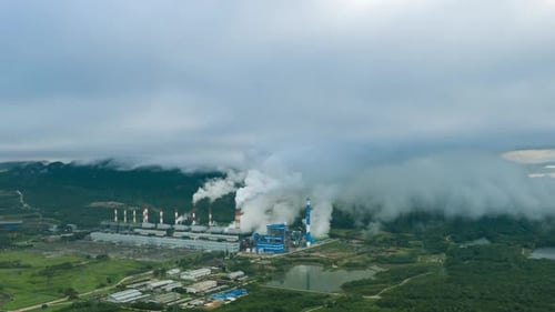 Aerial view over coal-fired power plant at sun dawn with smoke from cooling,