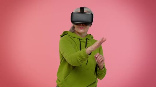 Senior Woman Using VR Headset on Pink Background